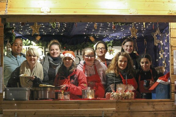 In der weihnachtlich geschmückten Holzhütte werden die Besucher willkommen geheißen, hier von der Verselbständigung Schillerstraße  