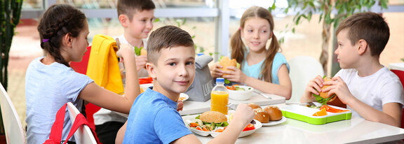 Kinder essen gemeinsam zu Mittag und unterhalten sich